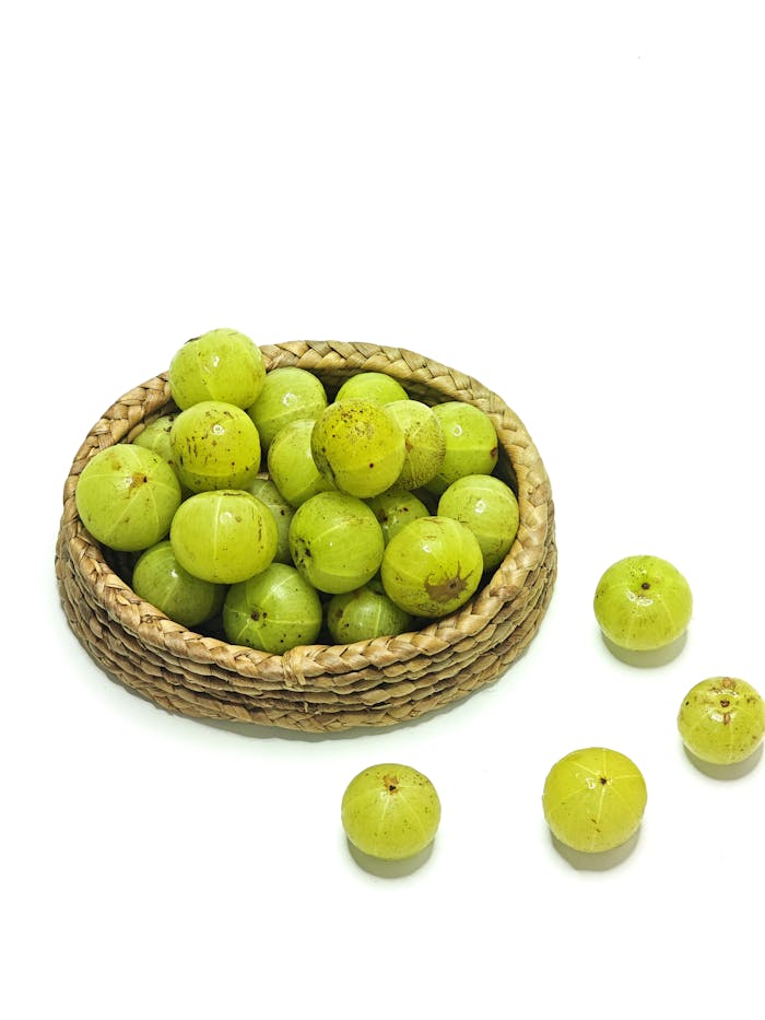 services-04 A wicker basket filled with vibrant green Indian gooseberries on a white background.